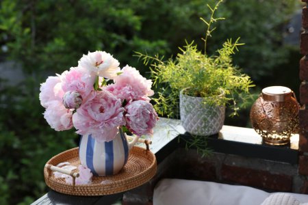 Foto de Hermosas flores de peonía rosa en jarrón en barandilla balcón al aire libre - Imagen libre de derechos