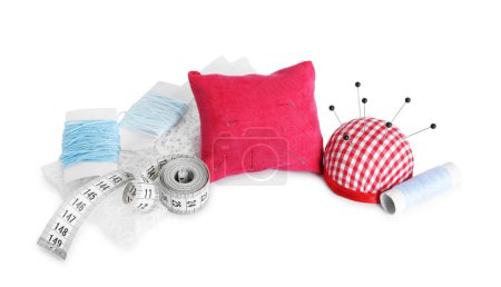 Pincushions, sewing pins, threads, cloth and measuring tape isolated on white