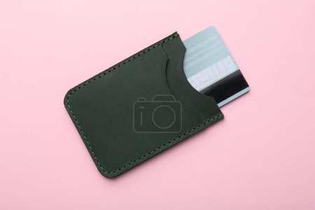 Lederkartenetui mit Kreditkarte auf rosa Hintergrund, Ansicht von oben