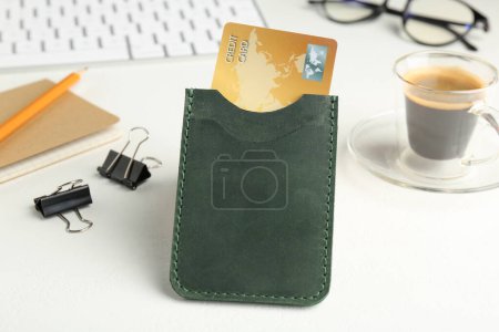 Téléchargez les photos : Porte-cartes en cuir avec carte de crédit, papeterie, café et clavier sur table blanche - en image libre de droit