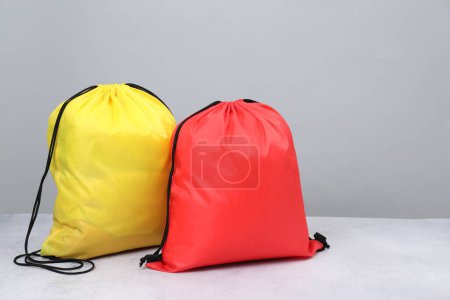 Two drawstring bags on light textured table. Space for text