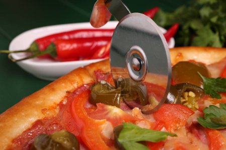 Cutting delicious pizza Diablo at table, closeup