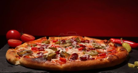 Delicious pizza Diablo on slate board against red background