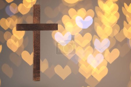 Wooden cross against blurred lights, closeup with space for text. Religion of Christianity
