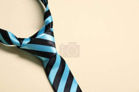 Striped necktie on beige background, above view. Space for text