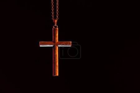 One cross with chain on black background, space for text. Religion of Christianity