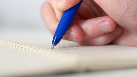 Foto de Hand makes notes in a paper notebook. Man writing with a pen at the table. Business notepad. Training, business and organization. Photo closeup - Imagen libre de derechos