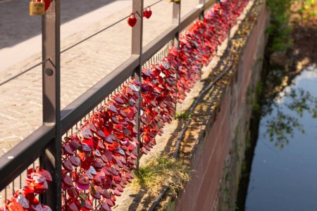 Photo for Locked red locks of lovers on an iron fence. Symbol of love and marriage. Romantic custom. Traditional culture in the city - Royalty Free Image