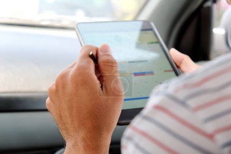 Téléchargez les photos : Homme d'affaires assis dans la voiture et en utilisant une tablette numérique. - en image libre de droit