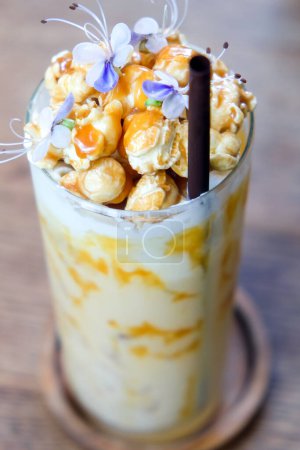 Photo for Iced caramel coffee with whipped cream and caramel popcorn on wooden table - Royalty Free Image