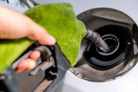 Nahaufnahme des Nachfüllens eines Autos mit Kraftstoff von Hand an einer Tankstelle, grüne Zapfpistole, Energiekonzept