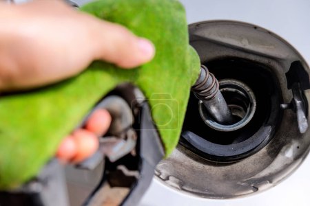 Foto de Primer plano imagen de la mano de recarga de un coche con combustible en una gasolinera, boquilla de combustible verde, concepto de energía - Imagen libre de derechos