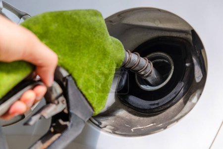 Nahaufnahme des Nachfüllens eines Autos mit Kraftstoff von Hand an einer Tankstelle, grüne Zapfpistole, Energiekonzept