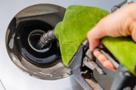 Téléchargez les photos : Image rapprochée du remplissage manuel d'une voiture avec du carburant dans une station-service, buse de carburant verte, concept énergétique - en image libre de droit
