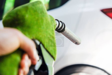 Photo for Close up image of hand refilling a car with fuel at a gas station, green fuel nozzle,energy concept - Royalty Free Image