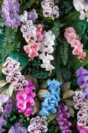 Foto de Flor de imitación, coloridas orquídeas artificiales en el jardín. Hermosas flores fondo. - Imagen libre de derechos