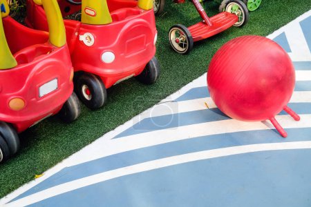 Vista superior de una vibrante escena de patio con coches de juguete rojos y una bola