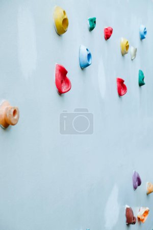 Close-up of vibrant climbing grips attached to a wall at an outdoor climbing gym