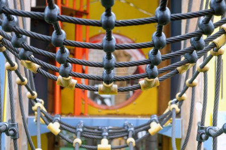 Photo for Close-up view of colorful playground rope bridge for children's outdoor recreational equipment in a public park. Ensuring safety and durability for a fun and adventurous playtime - Royalty Free Image