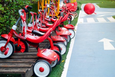 Rote Dreiräder reihen sich neben einem Parcours auf einem Kinderspielplatz