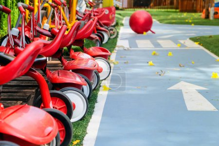 Téléchargez les photos : Tricycle rouge dans le parc, aire de jeux pour enfants dans le parc - en image libre de droit