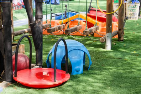Téléchargez les photos : Aire de jeux dans le parc avec sièges bleus et rouges et balançoires. - en image libre de droit