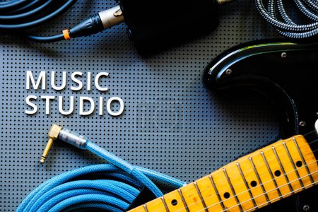 Foto de Guitarra eléctrica, Instumentos y cable sobre un fondo gris con la palabra Music Studio. Concepto musical - Imagen libre de derechos