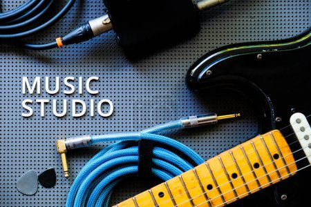 Téléchargez les photos : Guitare électrique, Instuments et câble sur fond gris avec le mot Music Studio. Concept de musique - en image libre de droit