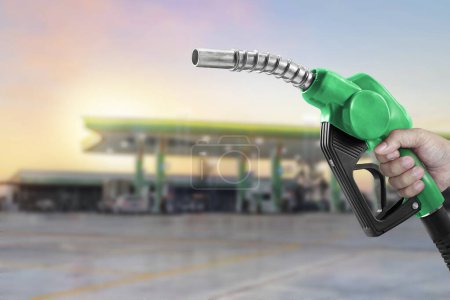 Photo for Holding a fuel nozzle against with gas station blurred background - Royalty Free Image
