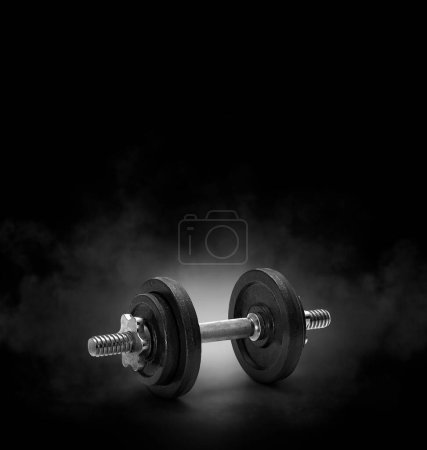 Photo for Black dumbbell with on black background with smoke - Royalty Free Image