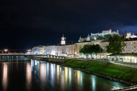 Foto de Salzburgo, Austria, 15 de agosto de 2022. Fascinante foto nocturna del centro histórico con vistas al río. Detrás, en la colina, el fuerte. Copiar espacio. - Imagen libre de derechos