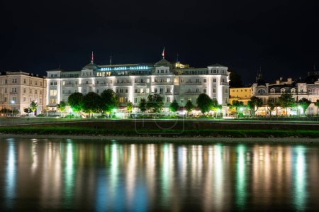 Salzburg, Austria, August 15, 2022. Iconic night image of the luxury hotel Sacher, reflected in the waters of the Salzach river. Copy space.