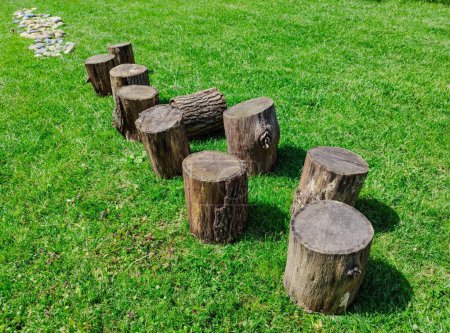Foto de Una ruta a realizar descalzo: troncos de madera sobre un césped seguido de una de piedras redondeadas. Hermoso día soleado. - Imagen libre de derechos