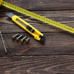 Tape measure, building knife, screws on wooden table, work tools