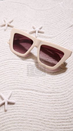 Photo for Beige sunglasses on sand, summer beach accessories - Royalty Free Image
