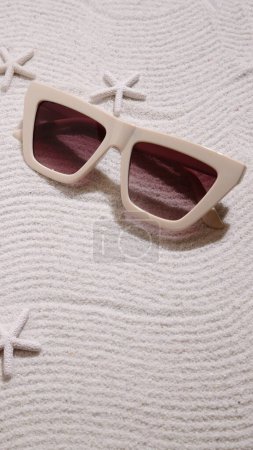 Photo for Beige sunglasses on sand, summer beach accessories - Royalty Free Image