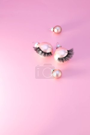 Photo for False eyelashes on Christmas tree ball decoration, pink background - Royalty Free Image