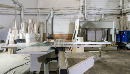 Foto de A large sliding table saw machine with dust hood in industrial factory producing wooden furniture parts. - Imagen libre de derechos