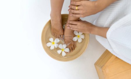 Photo for Female feet soaked in a bowl filled with water and flower petals, a depiction of relaxation and luxurious self-care. - Royalty Free Image