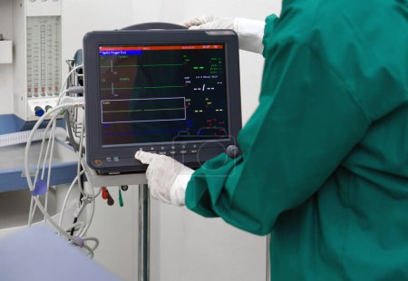 Foto de Monitor de paciente multiparamétrico en quirófano, controlado por enfermera en uniforme de bata verde quirúrgica. - Imagen libre de derechos
