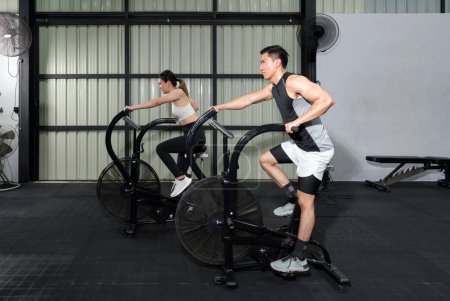 Photo for Fitness Couple Cycling on Stationary Bikes in Health Club - Royalty Free Image