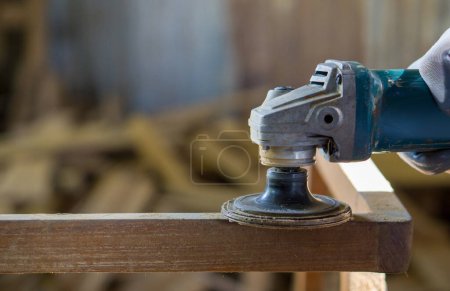 Téléchargez les photos : Une personne travaille avec un outil électrique, envoyant de la sciure voler pendant qu'elle coupe ou forme un morceau de bois. - en image libre de droit