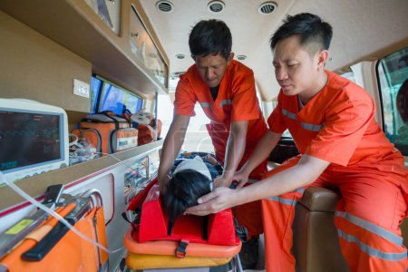 Zwei Sanitäter in orangefarbenen Uniformen helfen einem Patienten im Krankenwagen.