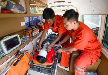Eine Person trägt eine Sauerstoffmaske und holt sich Hilfe von Sanitätern in orangefarbener Uniform im Krankenwagen.