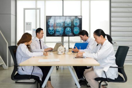 Group of medical professional engaged in a discussion or meeting in a medical office. A large monitor displaying multiple MRI brain scans, to revolve around patient diagnosis and treatment planning.