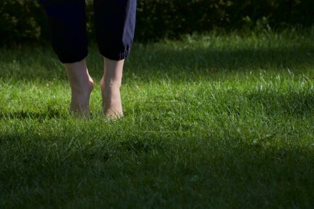 Téléchargez les photos : Image de pieds femelles nus debout sur de l'herbe fraîche humide debout sur les pointe des pieds vue de face - en image libre de droit
