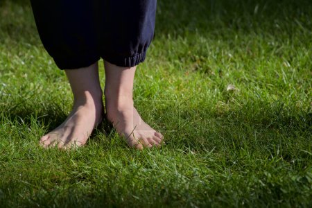Téléchargez les photos : Image de pieds femelles nus debout sur l'herbe fraîche humide vue de face - en image libre de droit