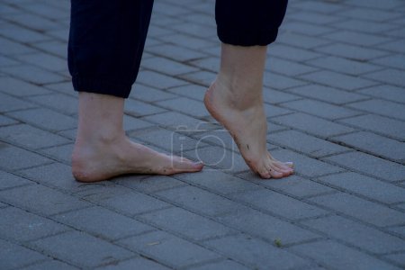 Téléchargez les photos : Image de pieds féminins nus debout sur le trottoir en brique grise faisant une vue de côté étape - en image libre de droit