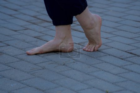 Téléchargez les photos : Image de pieds féminins nus debout sur un trottoir en brique grise faisant un pas - en image libre de droit