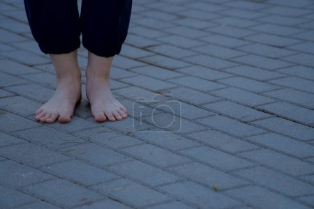 Téléchargez les photos : Image de pieds féminins nus debout sur le trottoir en brique grise vue de face - en image libre de droit